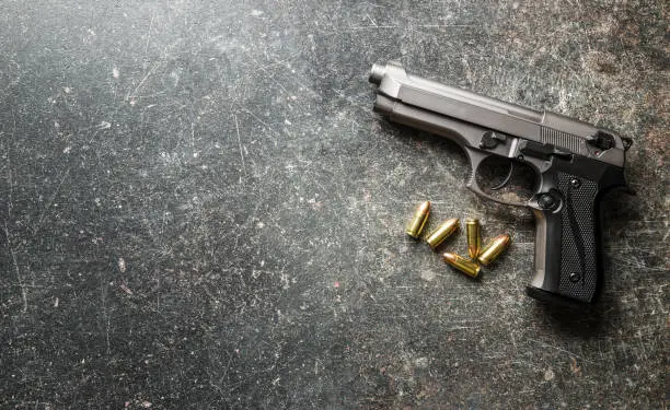 9mm pistol bullets and handgun on black table.